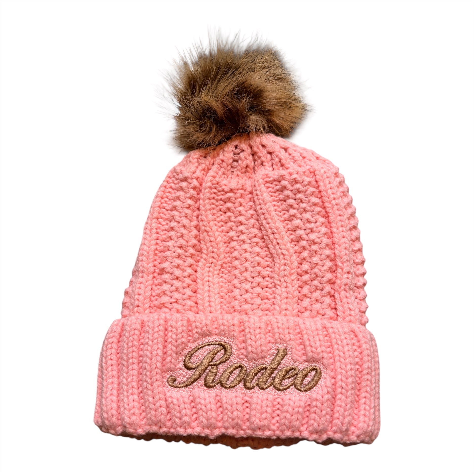 Pink knit beanie with fur pom-pom and 'Rodeo' embroidery on a white background